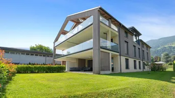 Modernes Mehrfamilienhaus mit Holzfassade, großen Balkonen und gepflegtem Gartenbereich.