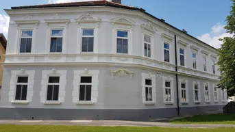 Elegantes historisches Gebäude mit frisch renovierter Fassade und dekorativen Stuckelementen an einem sonnigen Tag.