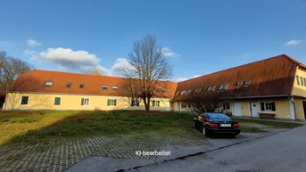 Gelbes Gebäude mit rotem Dach und einem Baum davor, umgeben von einer Grünfläche und Parkplatz.