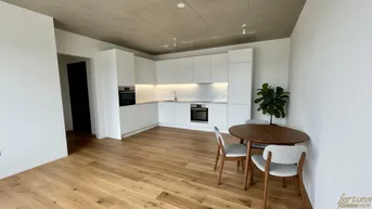 Moderne offene Küche mit weißen Hochglanzfronten, Holzboden und Essbereich.