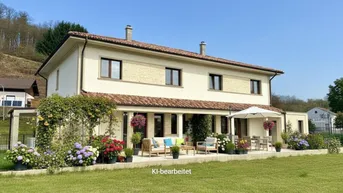 Großzügige Terrasse mit bequemen Gartenmöbeln und blühenden Pflanzen, umgeben von einem gepflegten Rasen.