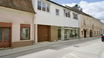 Fassade eines Gebäudes an einer Straße mit Geschäften im Erdgeschoss und Wohnungen darüber.