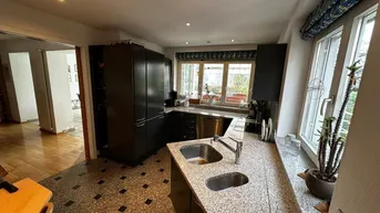 Geräumige Küche mit dunklen Schränken, Granitarbeitsplatten und großem Fensterbereich mit viel Licht.