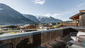 Sonniger Außenbereich mit Sitzgelegenheiten und weitem Blick über das Tal und die umliegende Berglandschaft.