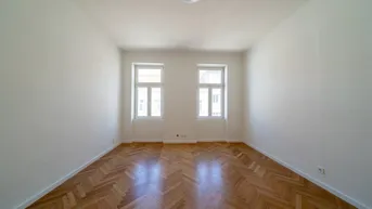 Helles Zimmer mit Fischgrätparkettboden und zwei großen Fenstern, ideal für Wohn- oder Schlafbereich.