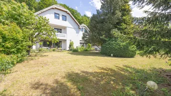 Weitläufiger Garten mit Rasenfläche und altem Baumbestand vor dem weißen Wohnhaus.