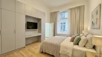 Helles Schlafzimmer mit Holzboden, Einbauschränken und Blick auf den Innenhof.