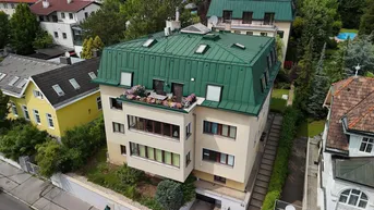 Luftaufnahme eines Mehrfamilienhauses mit grünem Dach und kleiner bepflanzter Terrasse.