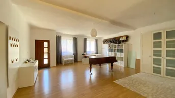 Geräumiger Wohnbereich mit hellem Holzboden, Klavier und viel natürlichem Tageslicht.