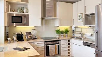 Moderne Küche mit weißen Schränken, Granitarbeitsplatten und integrierten Edelstahlgeräten, inklusive Mikrowelle und Backofen.