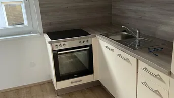Moderne Einbauküche mit hellen Fronten, Holzdekor und Fenster für Tageslicht.