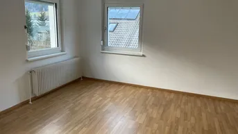 Helles Zimmer mit zwei Fenstern, Laminatboden und Blick auf die Umgebung.