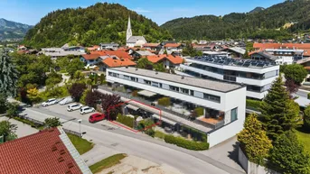 Moderne Wohnanlage in einer malerischen Berglandschaft mit Kirche und umliegenden Häusern.