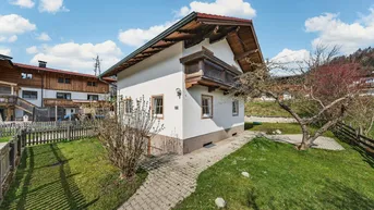 Charmantes Haus mit traditionellen Holzelementen und gepflegtem Garten in ländlicher Umgebung.