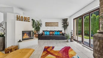 Gemütliches Wohnzimmer mit Kamin, großem Sofa und Zugang zur Terrasse oder Garten.