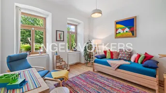 Helles Wohnzimmer mit Holzboden, farbenfroher Dekoration und Blick ins Grüne.