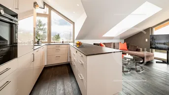 Moderne Küche mit hochwertigen Geräten und offenem Übergang zum Wohnbereich im Dachgeschoss.