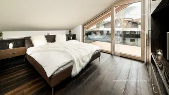 Helles Schlafzimmer mit Holzboden, großem Fenster und Blick auf die umliegende Landschaft.