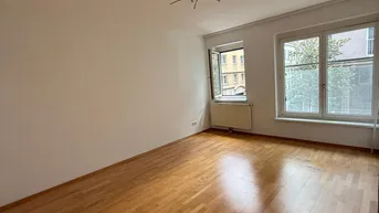 Helles, leeres Zimmer mit Parkettboden und zwei Fenstern, bereit zur individuellen Gestaltung.