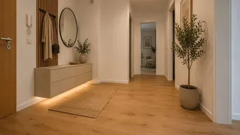 Heller Flur mit Holzboden, Garderobe, Spiegel und dekorativen Pflanzen.
