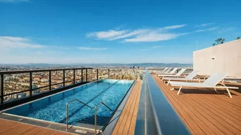 Dachterrassenpool mit atemberaubendem Stadtblick und Liegestühlen für entspannte Stunden.
