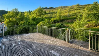 Große Holzterrasse mit Metallgeländer und weitem Blick auf die umliegenden Weinberge und grüne Hügel.
