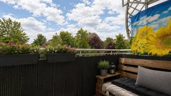 Gemütlicher Balkon mit Sitzgelegenheiten aus Paletten und Blumenkästen.