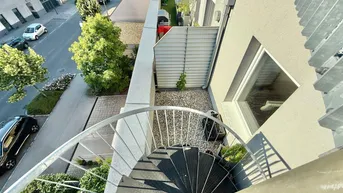 Blick von oben auf die Terrasse und die darunterliegende Straße mit parkenden Autos.