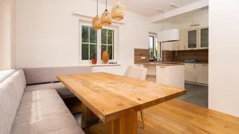 Helle Wohnküche mit Holztisch, Sitzbank und modernen Hängelampen, ideal für gemeinsame Mahlzeiten.