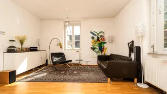 Helles Wohnzimmer mit Parkettboden, bequemen Ledermöbeln und einem farbenfrohen Kunstwerk an der Wand.