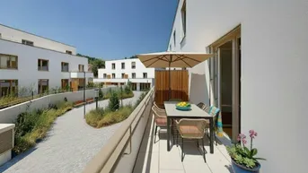 Geräumiger Balkon mit Sitzgelegenheiten und Sonnenschirm, umgeben von modernen Wohngebäuden und Grünflächen.