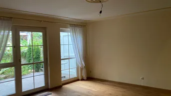 Helles Wohnzimmer mit Parkettboden, Stuckdecke und direktem Zugang zur Terrasse.