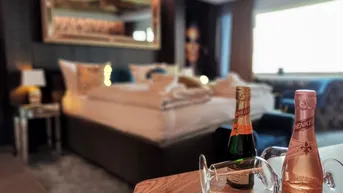 Gemütliches Schlafzimmer mit Doppelbett, elegantem Spiegel und Champagnerflaschen auf dem Nachttisch.