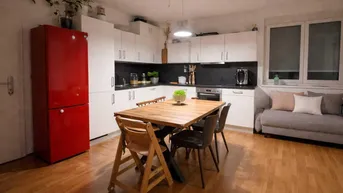 Offener Wohnbereich mit integrierter Küche, Esstisch und Sofa bei Abendbeleuchtung.