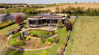 Luftaufnahme des modernen Hauses mit Gründach, Naturpool und weitläufigem Garten in ländlicher Umgebung.