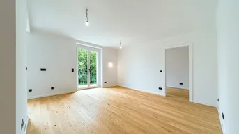 Helles, leeres Zimmer mit neuem Eichenparkettboden und Zugang zu einem Balkon.