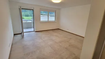 Heller, leerer Raum mit Fliesenboden und Zugang zu einem Balkon, umgeben von grüner Natur.