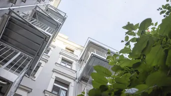 Blick nach oben auf die Fassade eines Altbaus mit mehreren Balkonen.