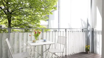 Gemütlicher Balkon mit Holzboden, Sitzgelegenheiten und Blick ins Grüne.