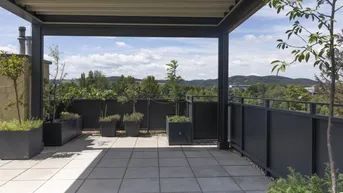 Geräumige Dachterrasse mit Pergola, Fliesenboden und weitem Ausblick.