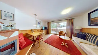 Gemütlicher Wohn- und Essbereich mit Kamin, Holzboden und Zugang zum Balkon.