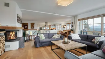 Geräumiger offener Wohn- und Essbereich mit Kamin, Holzboden und Zugang zum Balkon.