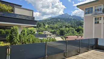 Terrasse mit Holzboden und Glasgeländer bietet einen weiten Blick auf die umliegende Berglandschaft.