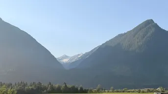 Majestätische Berglandschaft mit grünen Wäldern und einem klaren Himmel, die eine ruhige Aussicht bietet.