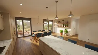 Heller offener Wohn- und Essbereich mit moderner Küche, Holzboden und Zugang zur Terrasse.