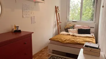 Helles Schlafzimmer mit Holzboden, Einzelbett und Fenster mit Blick ins Grüne.