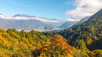 Herbstliche Berglandschaft mit weitem Blick über ein Tal und bewaldete Hänge.