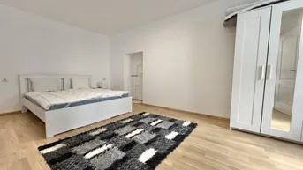 Helles Schlafzimmer mit Holzboden, weißem Bett und großem Kleiderschrank, ideal für erholsame Nächte.