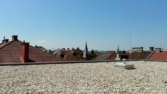 Weitläufige Dachfläche mit Kiesbelag und Panoramablick über die Stadt.