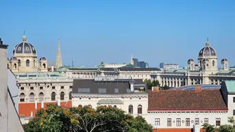 Panoramablick über die Wiener Innenstadt mit historischen Gebäuden und Kuppeln unter blauem Himmel.